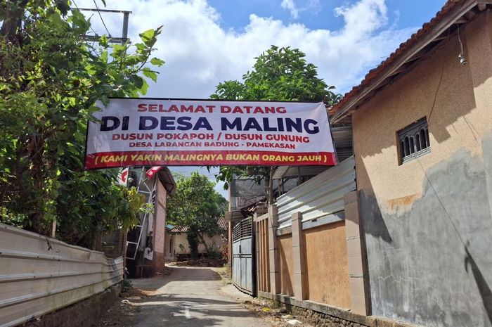 Spanduk bertuliskan 'Selamat Datang Di Desa Maling' yang terpasang di desa Larangan Badung, Palengaan, Pamekasan, Madura, Jawa Timur.