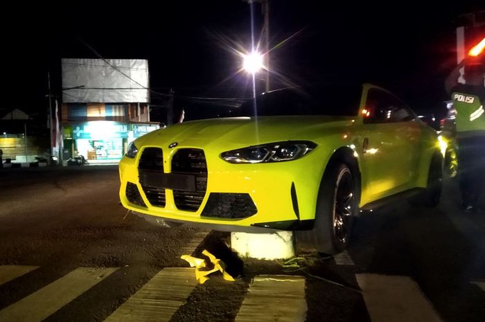 BMW M4 nyangkut di astsa pembatas jalan. 