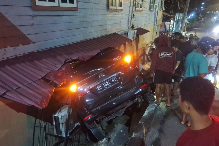 Toyota Avanza nungging di antara rumah dan jalan. Begini kronologinya
