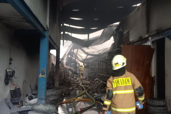 Petugas tampak berusaha memadamkan api yang membakar gudang dan produksi aksesori mobil di Jl Mangga Ubi No.6, Kapuk, Jakarta Barat, (2/10/25)