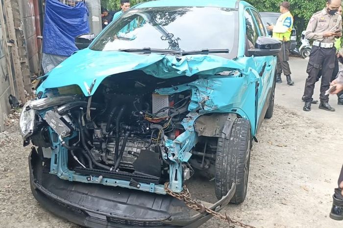 Taksi listrik Vinfast VF e34 milik Green SM yang menemper ekor kereta di pelintasan Jembatan Gantung, Cengkareng, Jakarta Barat, (10/10/25) siang.