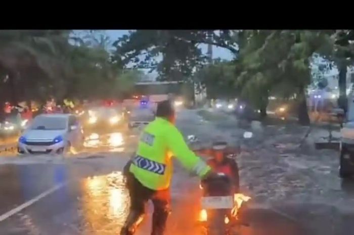 Aksi polisi mengevakuasi motor yang terbakar usai terendam banjir di ruas jalan Daan Mogot
