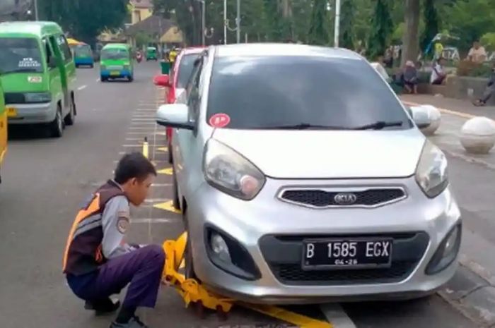 Petugas Dishub menggembok ban mobil yang parkir sembarangan di Alun-alun Kota Bogor