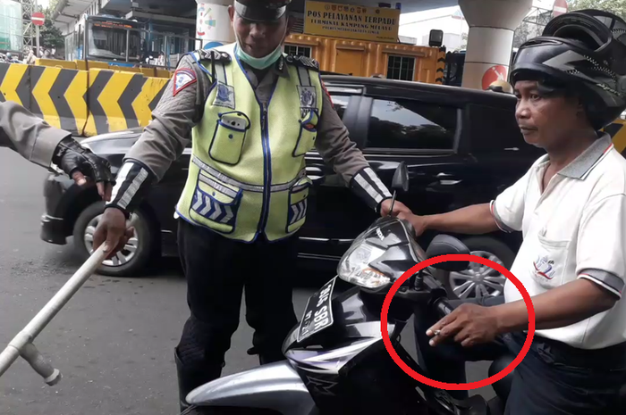 Dalam lingkaran merah, pengendara motor dihentikan Polisi karena kedapatan merokok di jalan