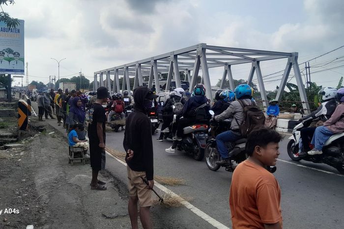 Aktivitas penyapu uang koin di jembatan Sewon, perbatasan Indramayu-Subang, Jawa Barat membuat arus lalu lintas pemudik tersendat