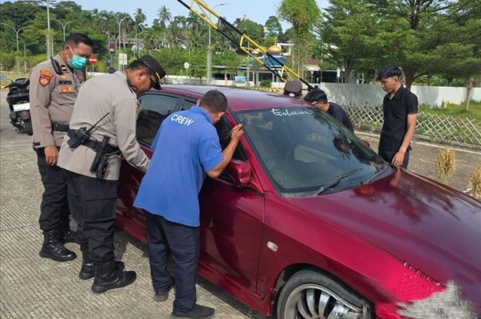 Polisi membantu membukakan pintu mobil sedan yang terkunci dan kunci kontaknya tertinggal di dalam di pelabuhan Bakauheni, Lampung Selatan, Lampung