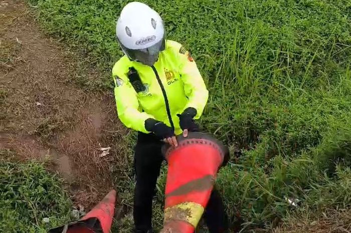 Anggota Satlantas Polres Indramayu saat memungut traffic cone yang diduga dirusak kemudian dibuang di selokan bahu jalan dekat Rest Area KM 130 Tol Cipali, Sabtu (28/3/2026)