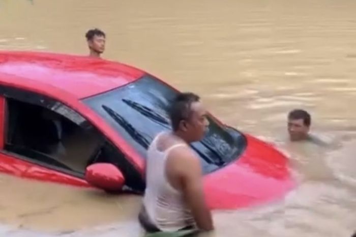 Warga gotong royong mengevakuasi Honda Brio yang hanyut terbawa banjir di desa Tanjungkerta, Kroya, Indramayu, Jawa Barat