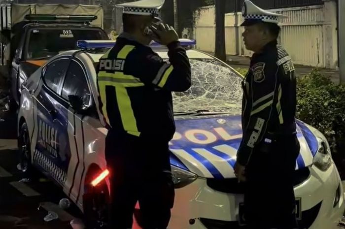Dua anggota Polisi di depan mobil patroli Satlantas Polres Metro Jakarta Pusat yang dirusak orang tak dikenal saat pengamanan perayaan HUT DKI Jakarta di Bundaran HI, Jakarta Pusat, (21/6/26) malam