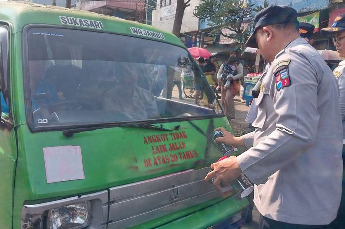 Petugas Dinas Perhubungan (Dishub) Kota Bogor menandai angkot tua yang nekat beroperasi dengan cat semprot bertuliskan 'Angkot Tidak Laik Jalan Di Atas 20 Tahun' dan tanda silang hitam di bodi depan