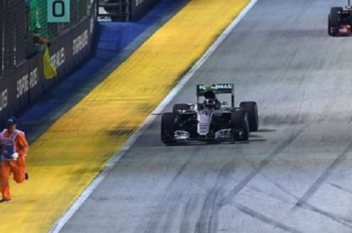 Seorang marshal berlari ke tepi lintasan untuk menghindari rombongan mobil F1 yang kembali berlomba 