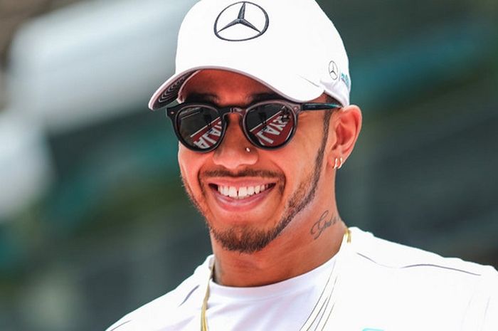 Lewis Hamilton tersenyum