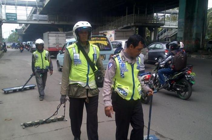 Relawan Tim Saber tengah membersihkan ranjau paku, foto: Tribunnews