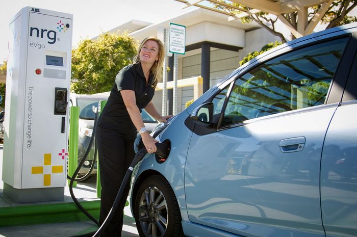 Wanita sedang megisi bahan bakar listrik di stasiun pengisian daya