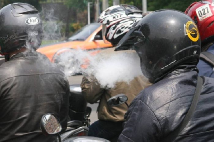 Naik motor sambil merokok  mengganggu orang lain
