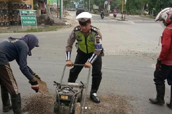 Personel satlantas Grobogan membantu menambal jalan berlubang.