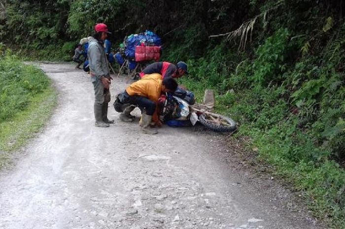 Tukang ojek Seko memperbaiki motor yang rusak dalam perjalanan.