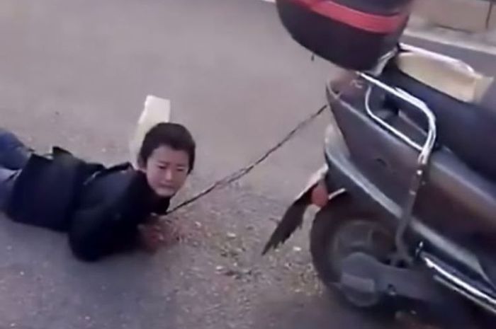 Penampakan seorang bocah laki-laki yang diikat dan diseret menggunakan motor lantaran mencuri uang dari tabungan keluarga