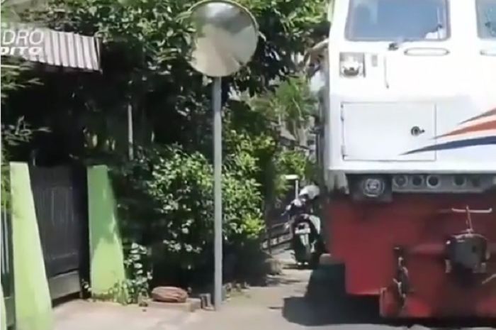 Sebuah Kereta Harus Menunggu Motor Matik Yang Parkir di Pinggir Rel