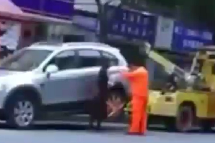 Seorang wanita emosi ketika mobilnya akan diderek petugas