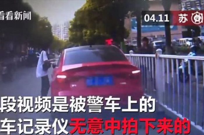 Gambar dalam rekaman yang menunjukkan momen di mana seorang wanita menempelkan tiket tilang palsu di mobilnya. 