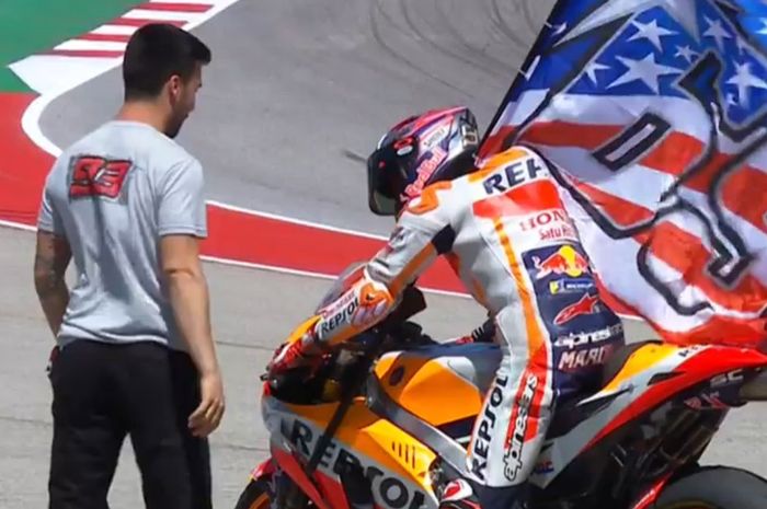 Marc Marquez merayakan kemenangan dengan mengibarkan bendera Nicky Hayden