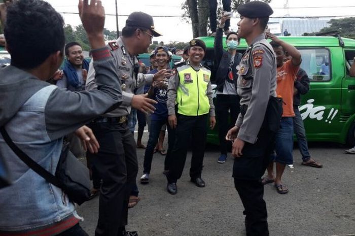 Personel Polisi menghibur peserta aksi unjuk rasa di depan Gedung Sate, Bandung, Selasa (08/5/2018)