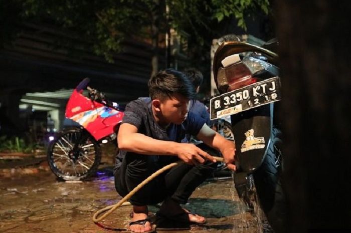 Ilustrasi cuci motor malam hari.