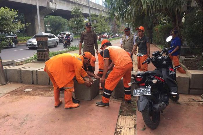 Petugas Penanganan Prasarana dan Saran Umum (PPSU) dan Satpol PP Kelurahan Menteng Atas, Jakarta Selatan merapikan beton pembatas yang dibongkar 