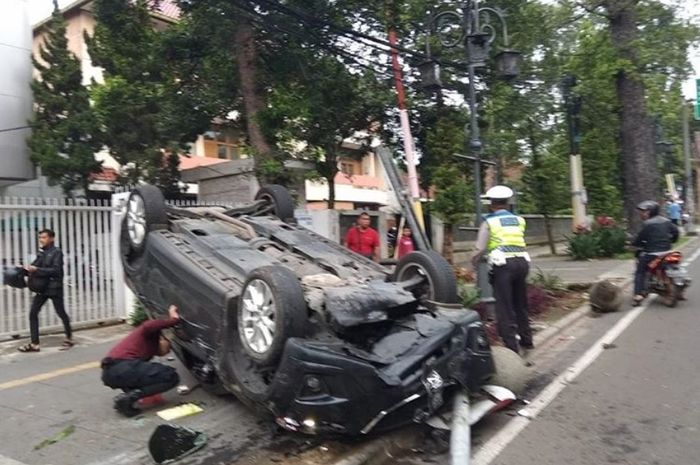 Mobil terbalik hantam bola batu dan rambu lalu lintas