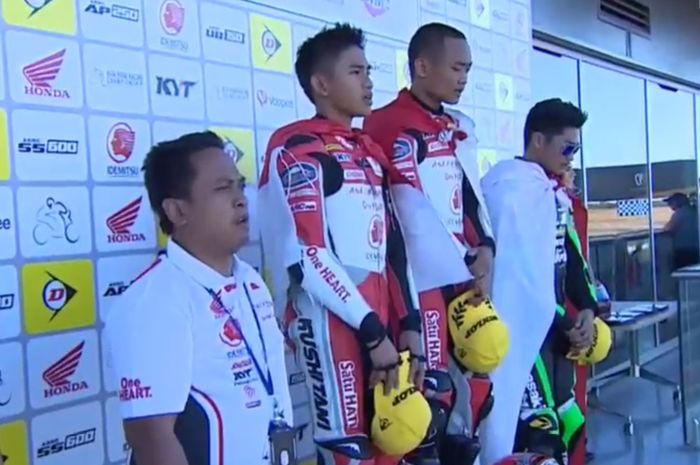 Tiga pembalap Indonesia saat menyanyikan lagu Indonesia Raya di atas podium