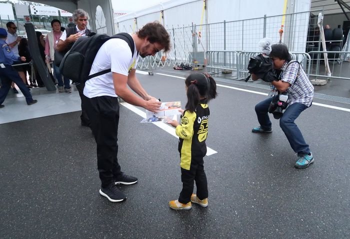 Pembalap tim McLaren Fernando Alonso memberi tanda tangan kepada fans F1 cilik asal Jepang ini