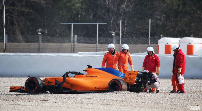 Fernando Alonso berjongkok mengecek mobilnya yang terhenti di gravel