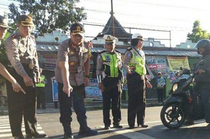 Kapolres Salatiga AKBP Gatot Hendro Hartono saat memperlihatkan analogi bahaya tidak menggunakan helm dengan buah semangka sebagai kepala pengguna jalan di perempatan Tingkir, Kamis (9/5/2019).  