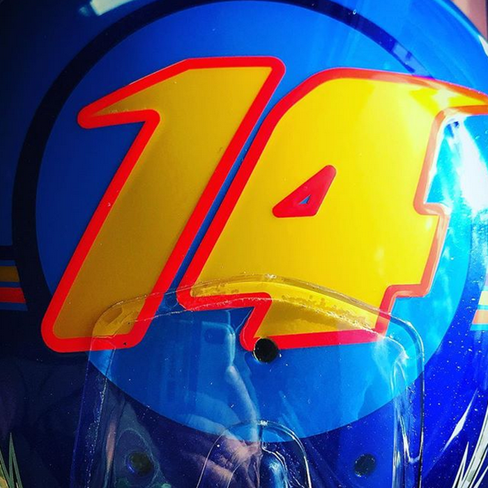 Angka 14 dengan garis warna merah mengelilingi kelir oranye di dalamnya, berada di bagian atas helm