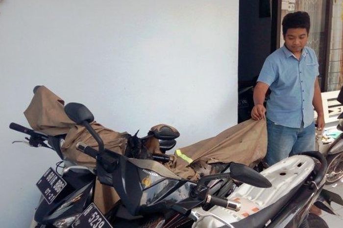 Adiyantoro (28) menunjukkan sepeda motornya yang terbakar di rumahnya