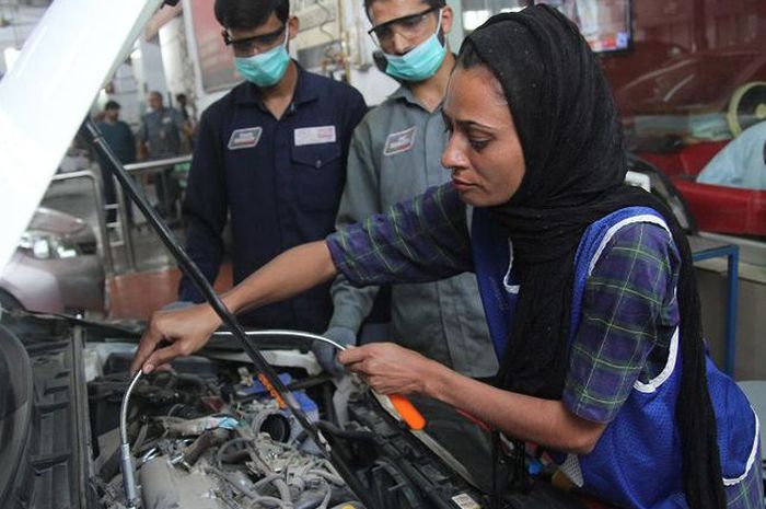 Uzma Nawaz (24) tengah memeriksa mesin sebuah mobil di sebuah bengkel di kota Multan, Pakistan