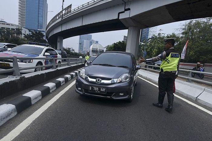 Petugas Ditlantas Polda Metro Jaya memberhentikan mobil berpelat nomor genap yang memasuki Jalan Gatot Soebroto, Jakarta, Rabu (1/8/2018). Petugas kepolisian mulai memberlakukan penindakan berupa tilang terhadap pengendara mobil yang melanggar di kawasan perluasan sistem ganjil-genap.(ANTARA FOTO/HAFIDZ MUBARAK A)