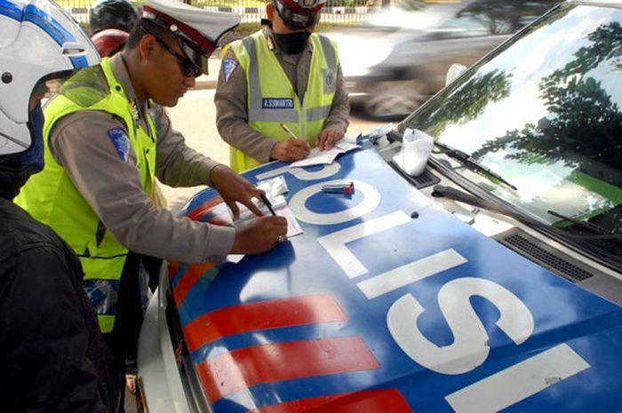 Ilustrasi polisi sedang bertugas memberikan surat tilang