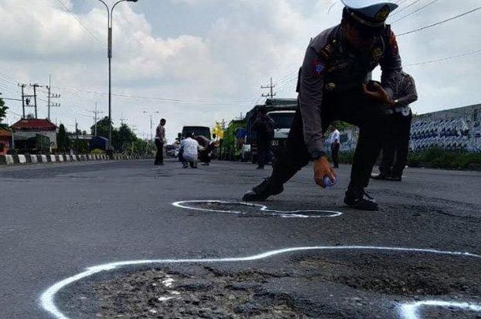 Polici mengecat  ulang jalan yang berlubang