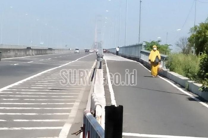 Seorang penumpang ojeg online harus menyusuri jembatan Suramadu dengan berjalan kaki