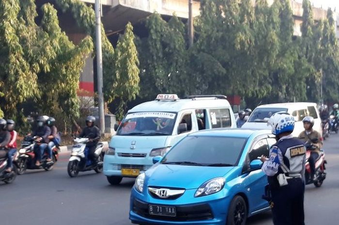 Petugas Dinas Perhubungan Jakarta Timur memantau kendaraan dalam uji coba ganjil-genap di Jalan DI P