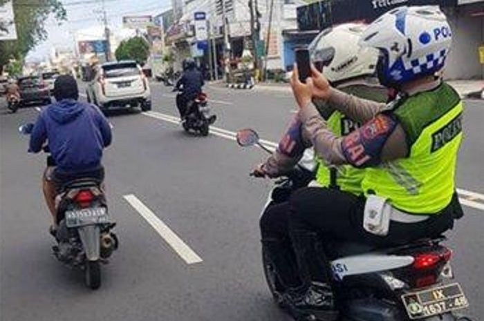Polisi melakukan tilang elektronik mobile ke pelanggar lalu lintas di jalan