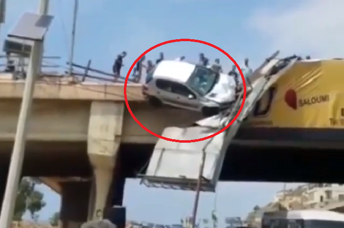 Sebuah mobil tersangkut di pembatas jembatan jalan
