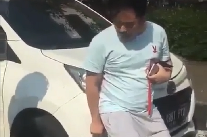 Seorang pria menolak mobilnya diderek petugas Dishub