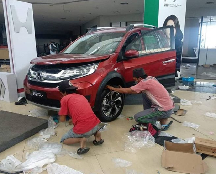 Oknum penjarah sedang melepas roda Honda Mobilio yang jadi display  di Mall