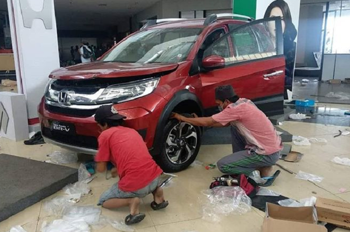 Oknum penjarah sedang melepas roda Honda Mobilio yang jadi display  di Mall