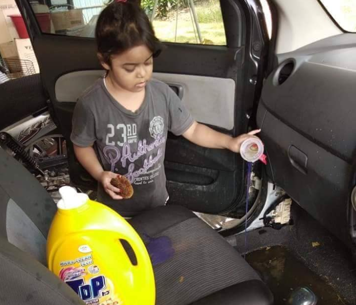 Anak kecil dengan menuangkan cairan saat membersihkan mobilnya