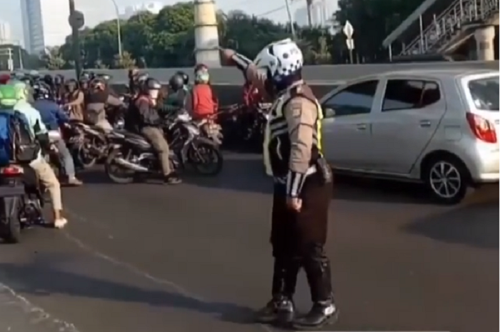 Seorang polisi menyuruh para pemotor putar balik di JLNT Casablanca
