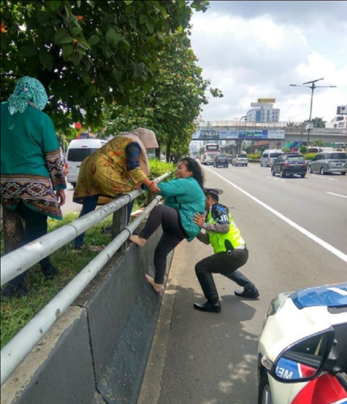 Seorang Petuga PJR membantu Ibu-ibu Memanjat Pembatas Jalan Tol